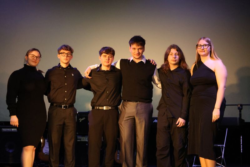 Zespół Kostanecki Band pozuje do wspólnego zdjęcia po występie na scenie.