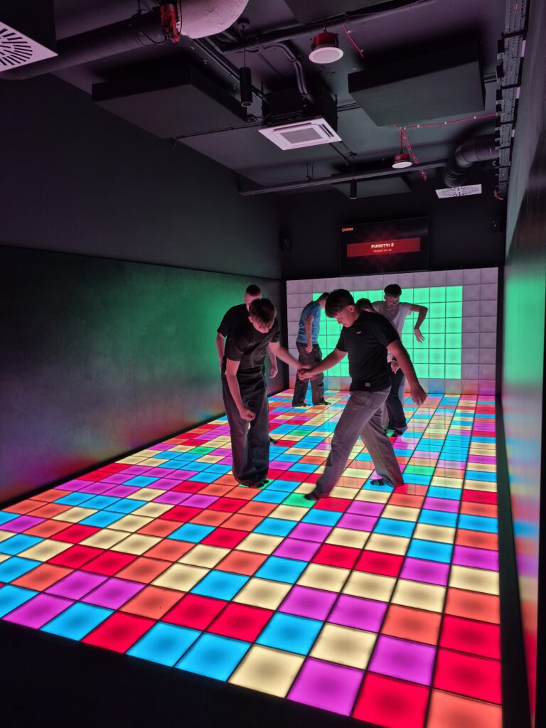 Grupa osób stojąca na kolorowej powierzchni