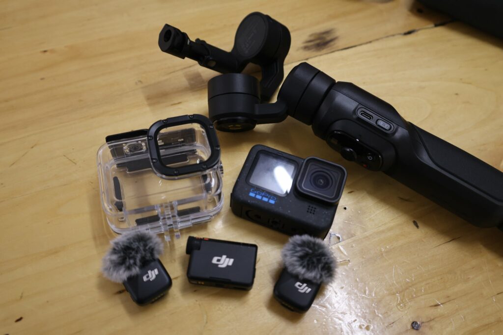 Zestaw do filmowania zawierający kamerę GoPro, gimbal oraz bezprzewodowe mikrofony DJI z osłonami przeciwwiatrowymi.