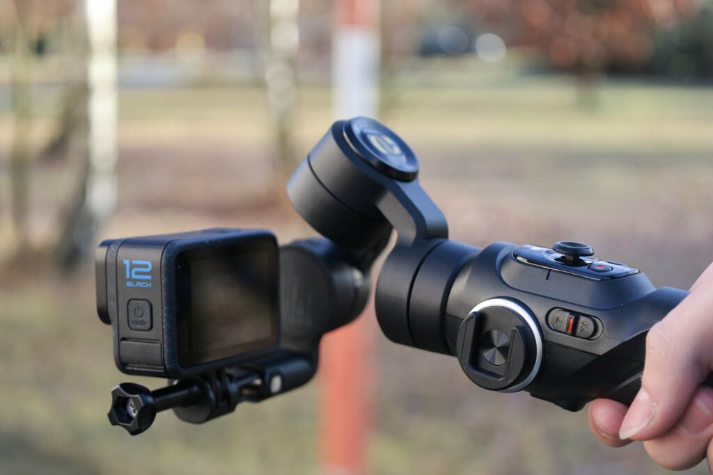 Ręczny stabilizator z zamocowaną na nim sportową kamerą GoPro Black 12.