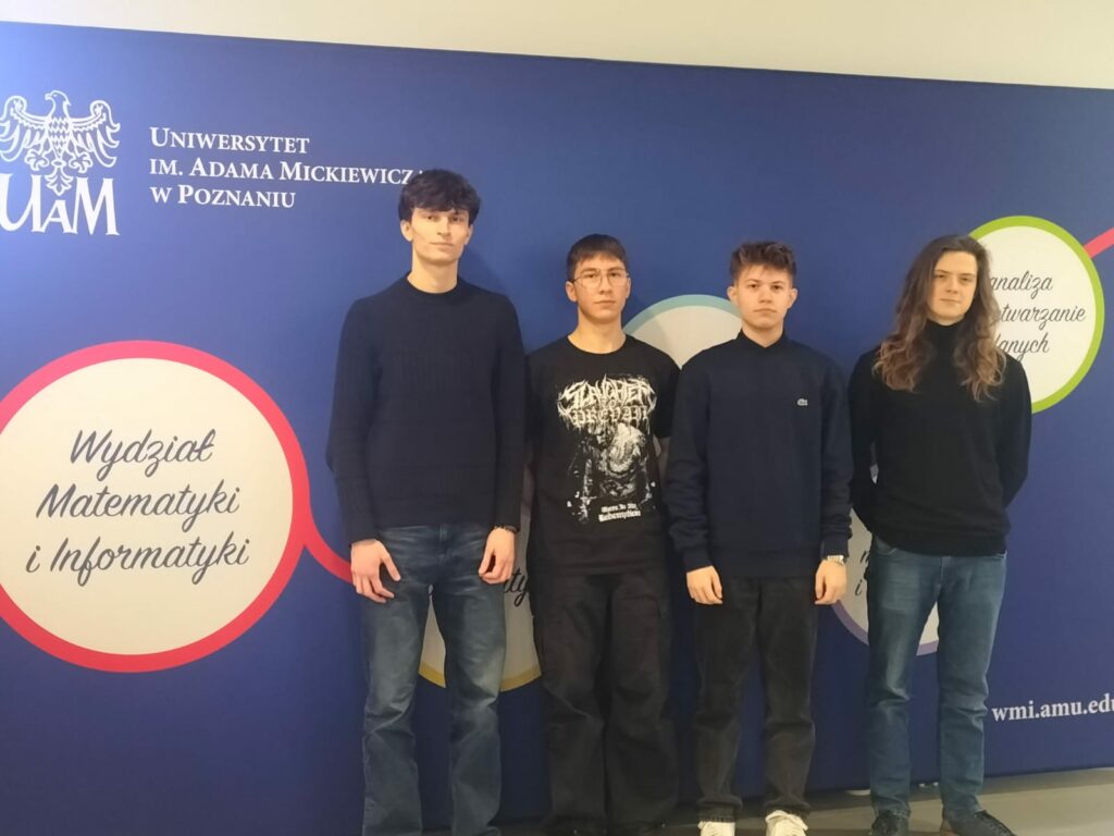 Czterech młodych mężczyzn stoi na tle ściany z logo Uniwersytetu im. Adama Mickiewicza w Poznaniu oraz napisem „Wydział Matematyki i Informatyki”.