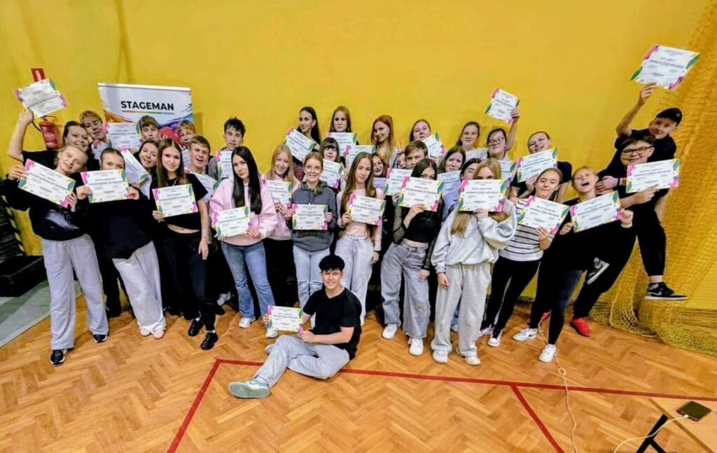 Grupa uczniów pozuje do zdjęcia trzymając certyfikaty w dłoniach