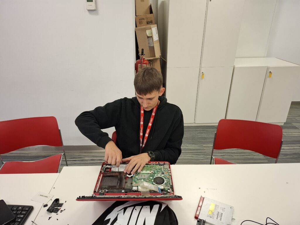 Uczeń naprawia komputer typu laptop