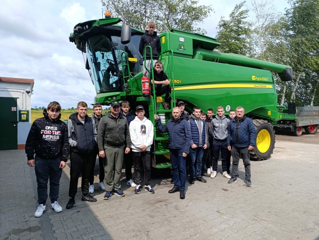 Uczniowie pozują do zdjęcia w tle zielony kombajn 