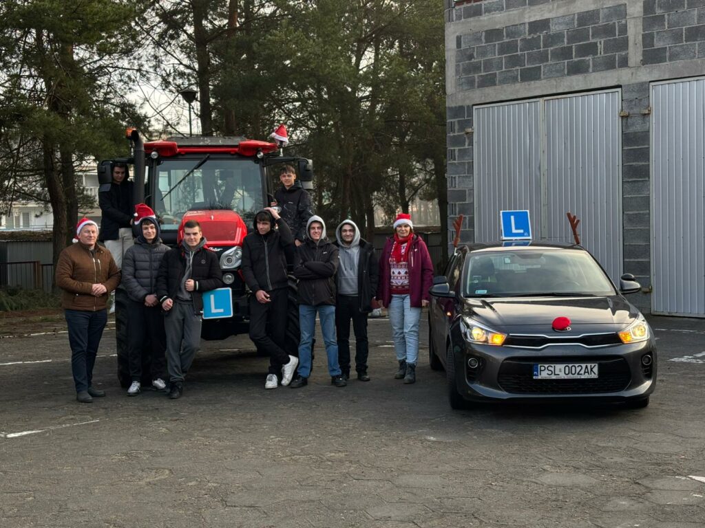 Uczniowie pozują do zdjęcia na tle ciągnika