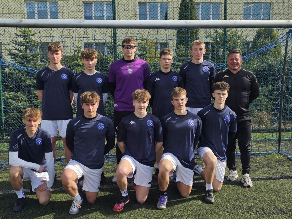 Grupa młodych mężczyzn pozująca do zdjęcia na zewnątrz, uśmiechając się do aparatu.