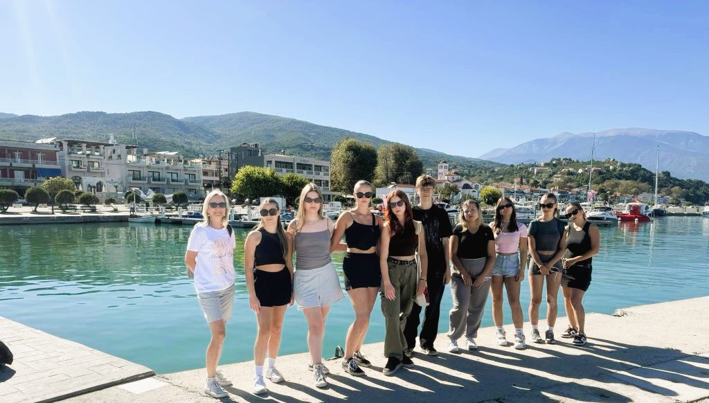 Grupa uczniów pozuje do zdjęcia na tle jeziora