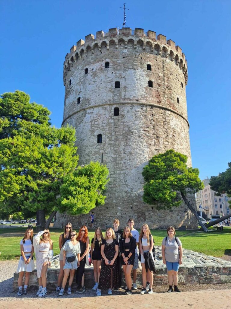 Grupa uczniów pozuje do zdjęcia na tle starego zamku