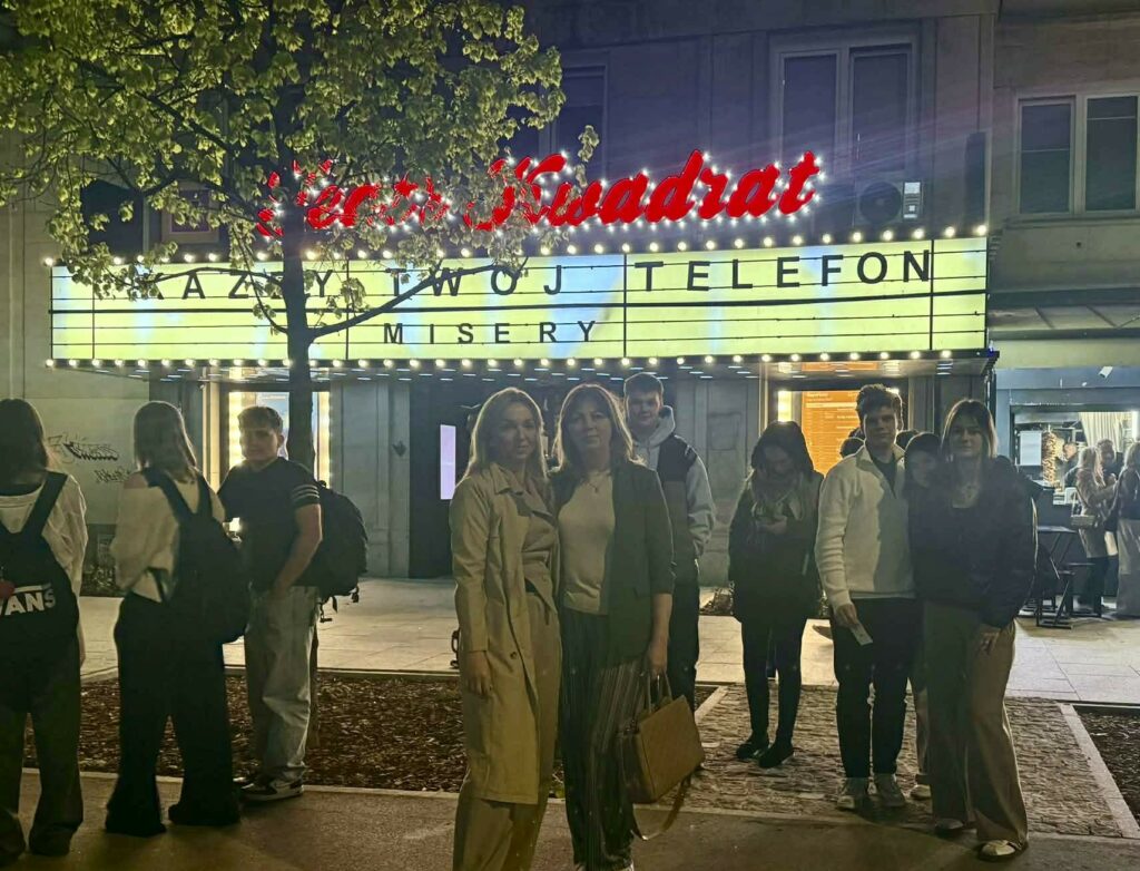 Grupa młodych ludzi stoi przed wejściem do kina Teatr Kwadrat z napisem na świetlnym banerze "AZBY TWÓJ TELEFON MISERY".