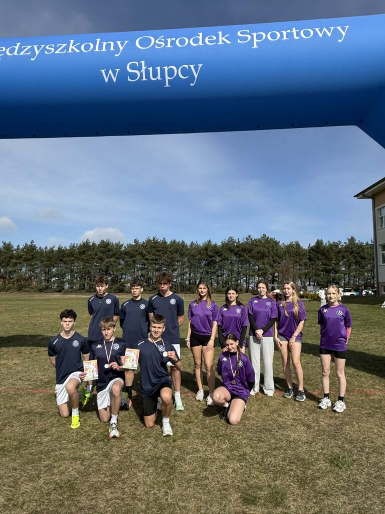 Zespół młodych sportowców w granatowych i fioletowych koszulkach z medalami i dyplomami na tle napisu „Międzyszkolny Ośrodek Sportowy w Słupcy”.