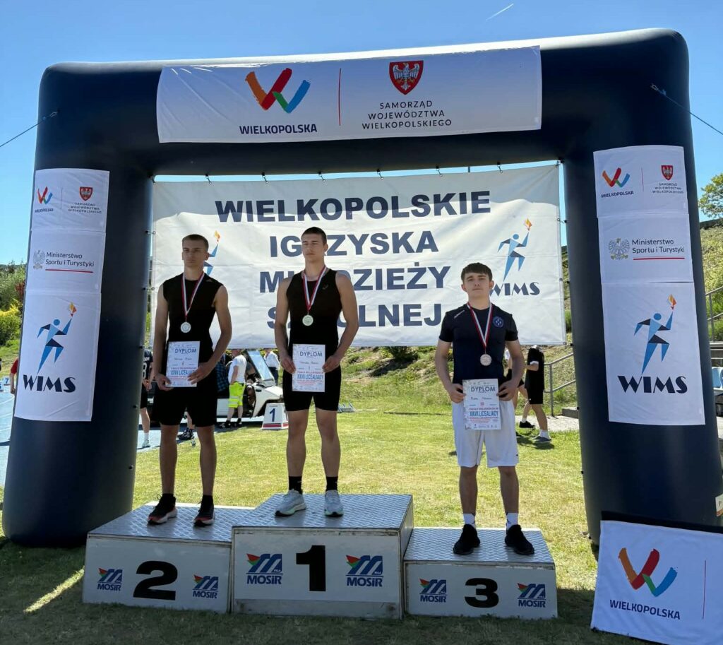 Trzech młodych zawodników stoi na podium z medalami i dyplomami podczas Wielkopolskich Igrzysk Młodzieży Szkolnej.