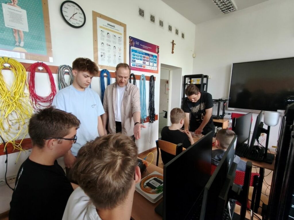 Uczniowie i nauczyciel patrzą na pomiar światłowodu