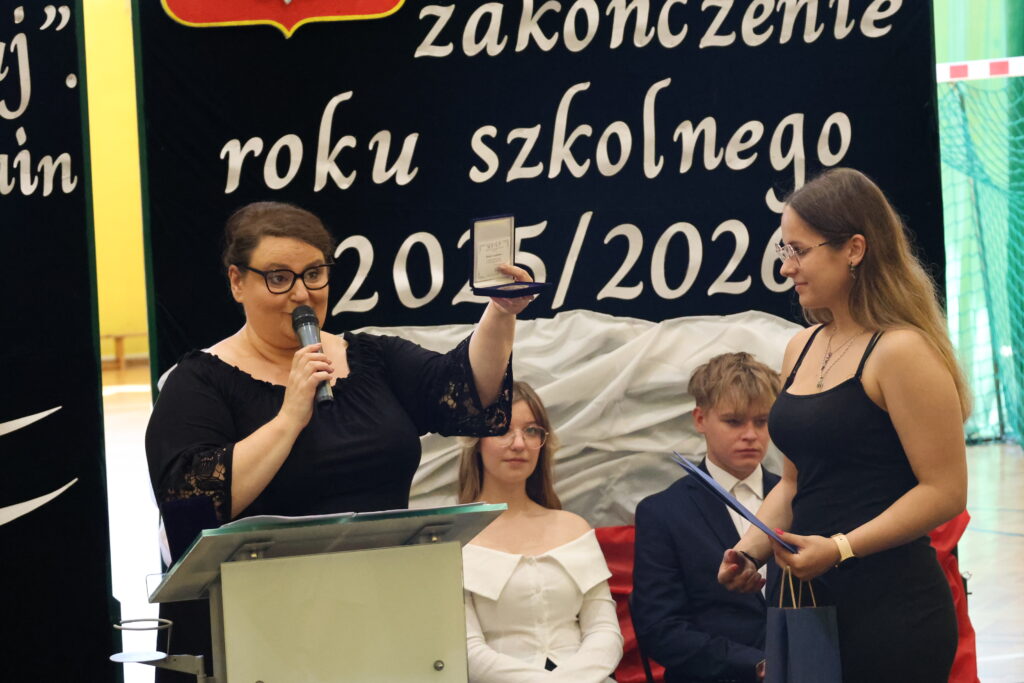 Nauczycielka wręcza nagrodę uczennicy podczas uroczystości zakończenia roku szkolnego 2025/2026.