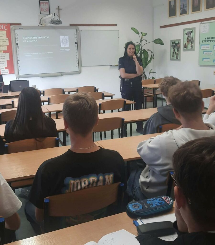 Policjantka prowadzi prelekcję dla uczniów w klasie na temat bezpiecznych praktyk za granicą.